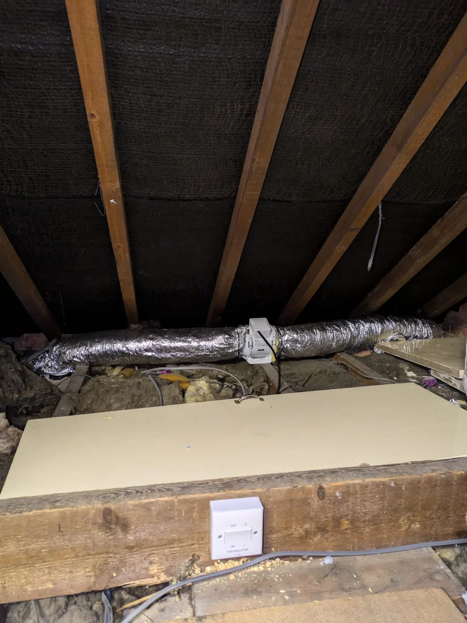Bathroom extractor ducting installed in loft space with fan isolator