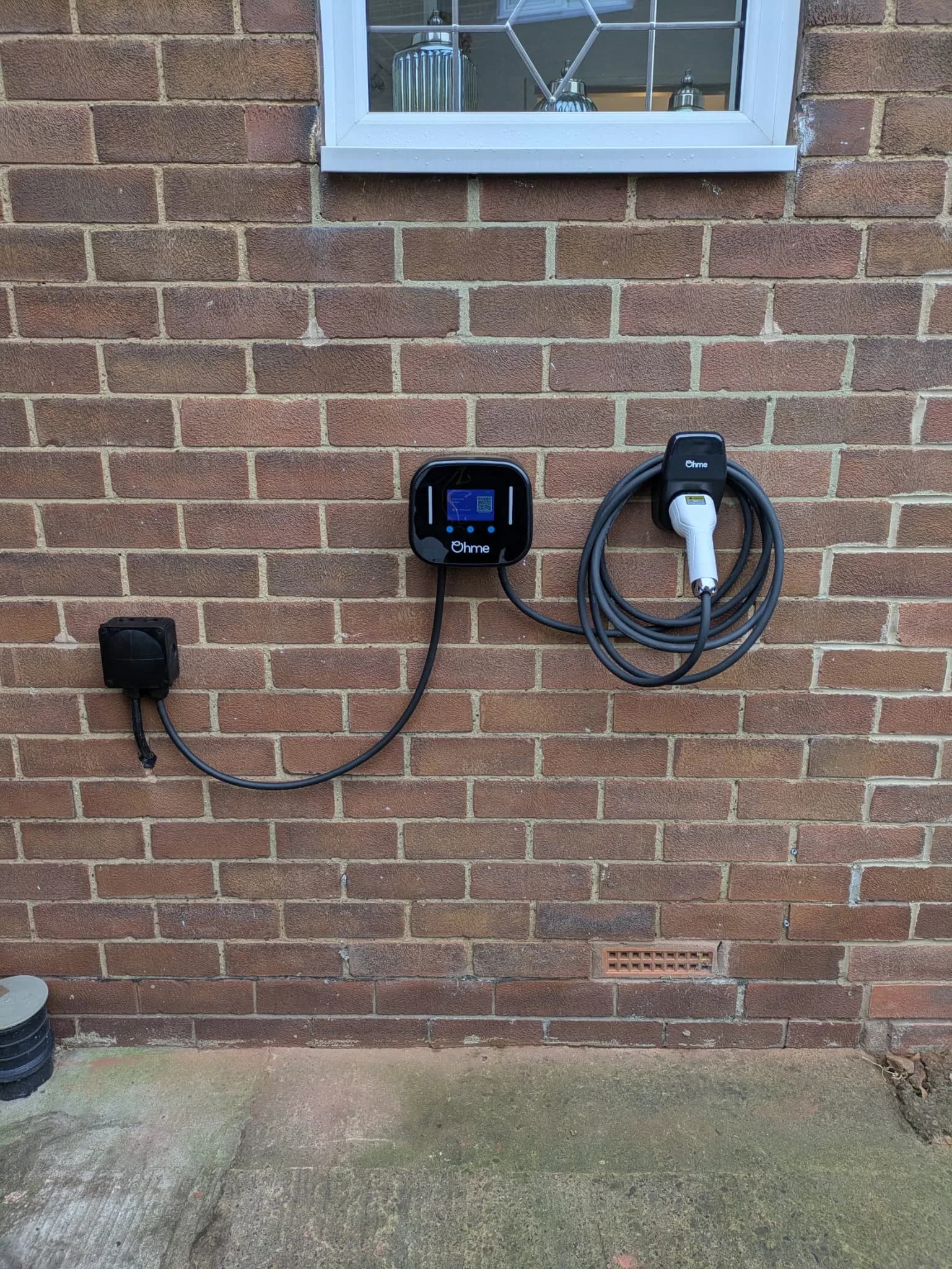 Ohme EV charger professionally installed on brick wall